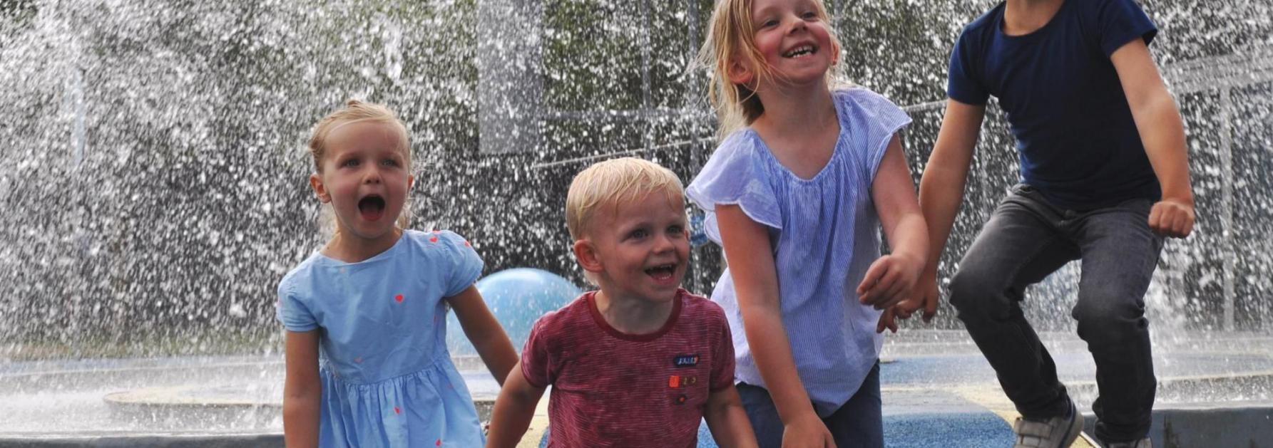 4 kinderen spelen in een waterfontein