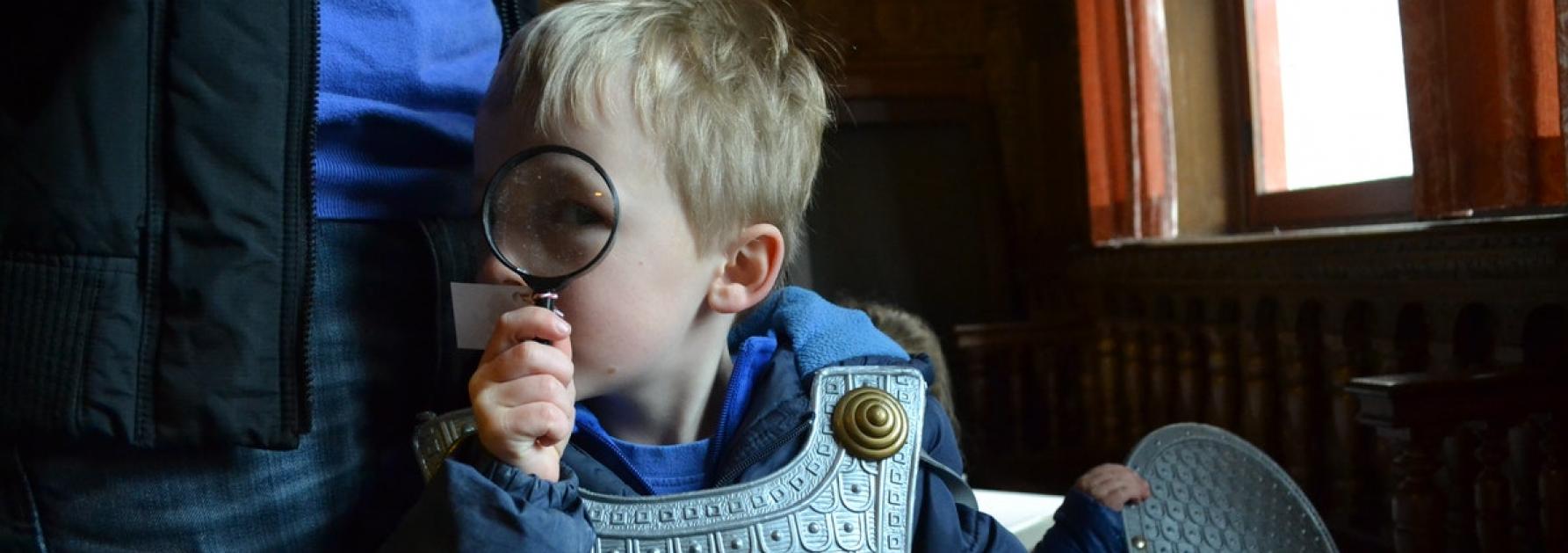 Jongen met speelgoedharnas en vergrootglas