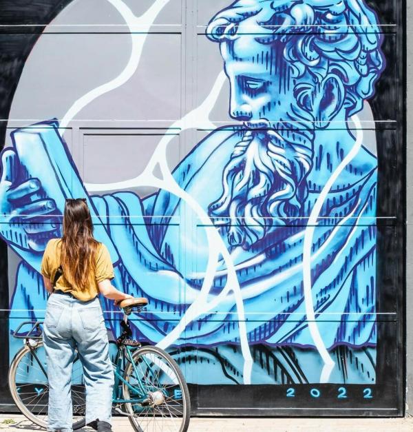Vrouw met fiets voor een muurschildering
