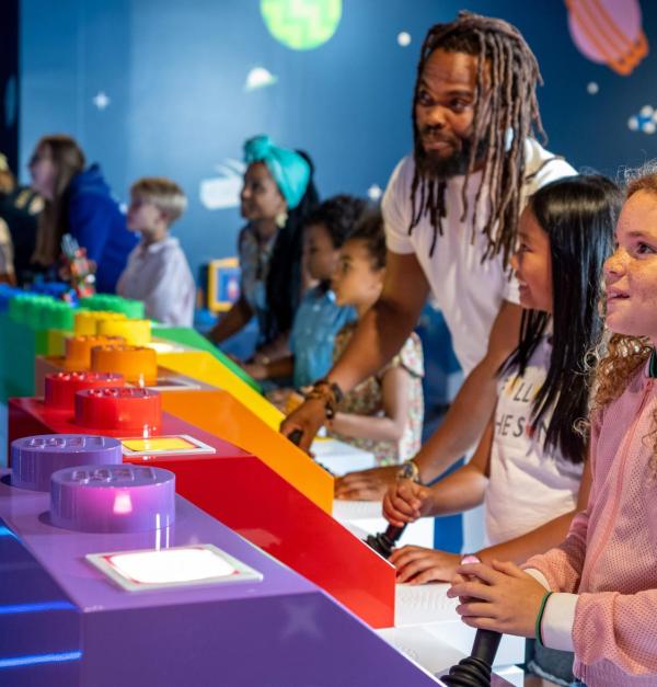 Man en kinderen spelen een spel in het LEGO Discovery Centre