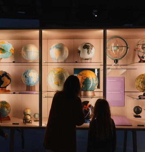 Afbeelding van gezin in het museum MAP - Mercator. Samen kijken ze naar wereldbollen.